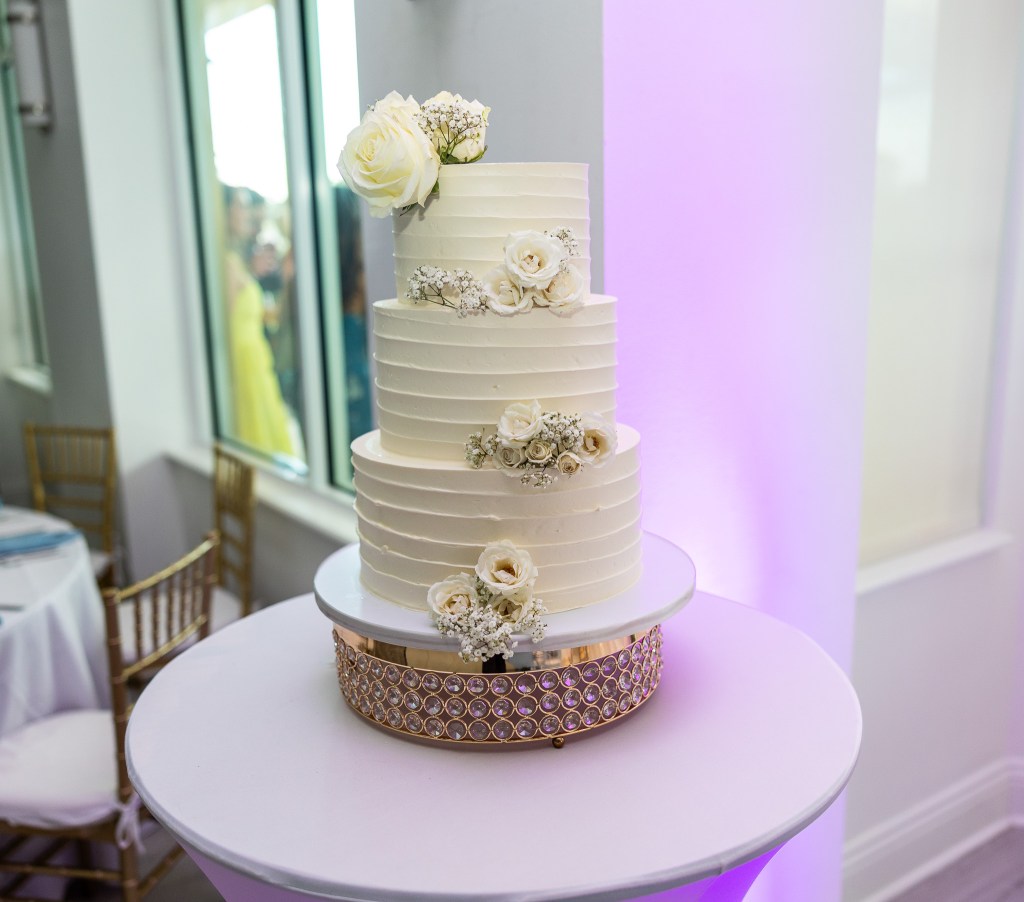 Palm Beach wedding venue reception with a luxury wedding cake adorned with luxury wedding flowers