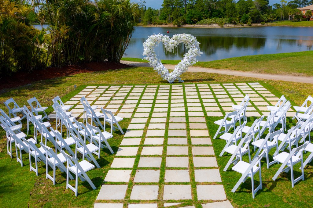 Spring Wedding Planning In Palm Beach Florida, outdoor wedding ceremony with white folding chairs, waterfront views and luxury flowers